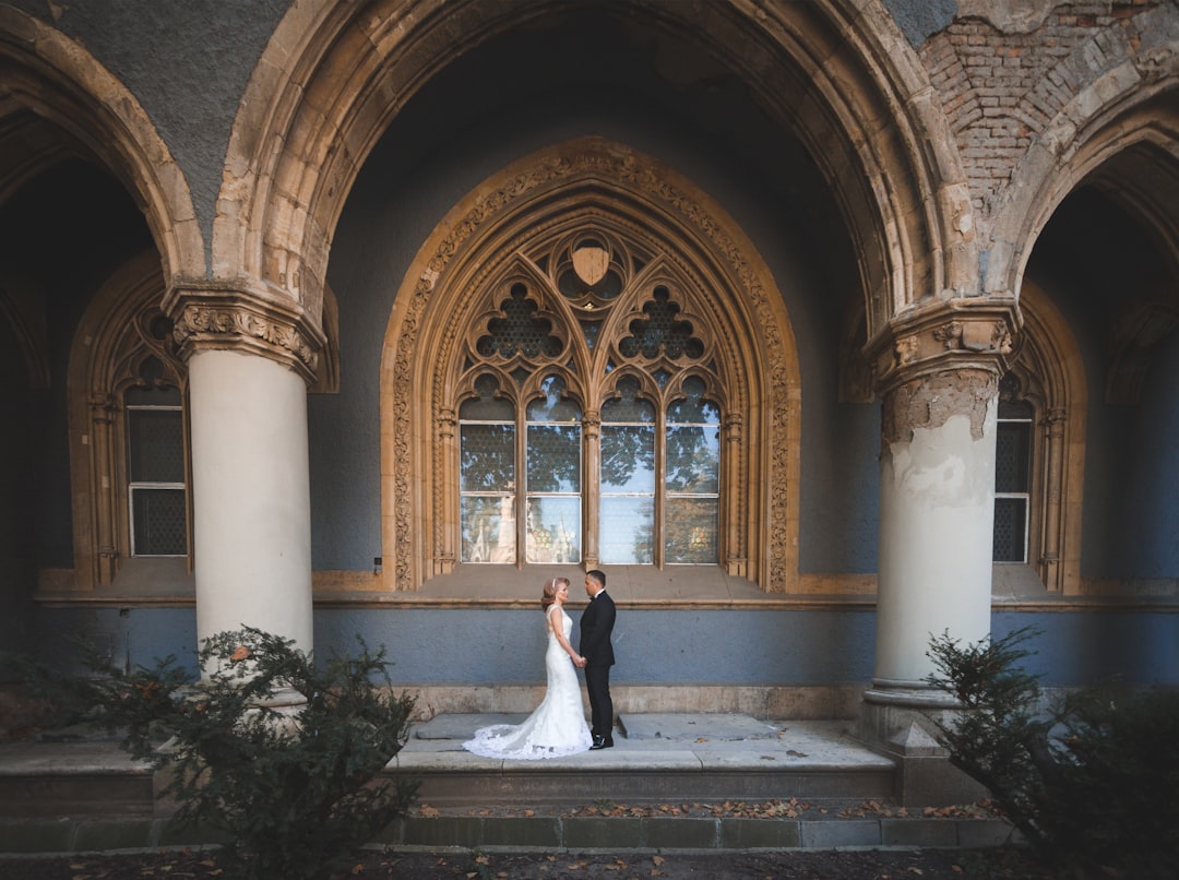 Bride and Groom holding hands, close to old church wall.