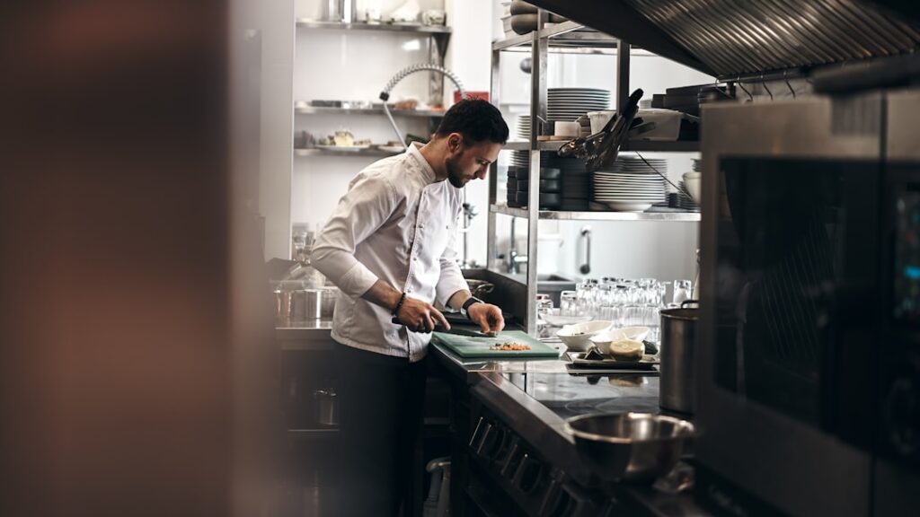 A chef dressed in a white coat working in a kitchen. @novokayn on Instagram
