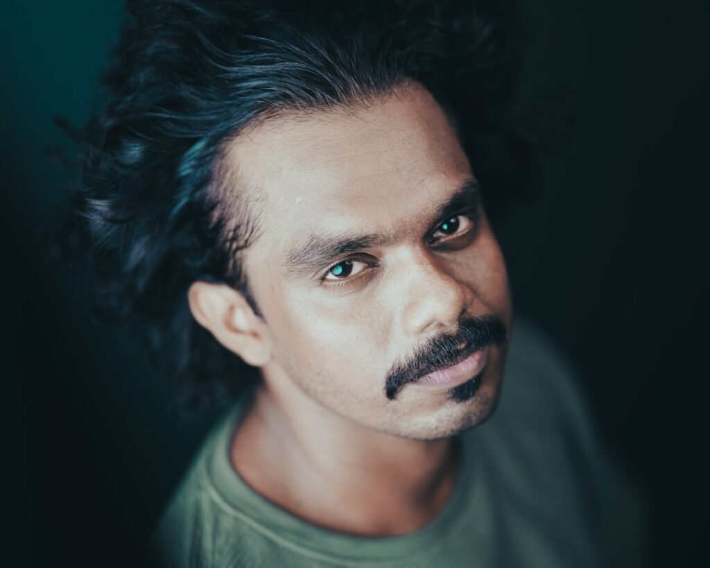 Man in a green round neck t-shirt looking at the camera